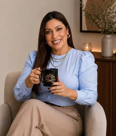 Eliane sorrindo, sentada numa poltrona com uma caneca nas mãos