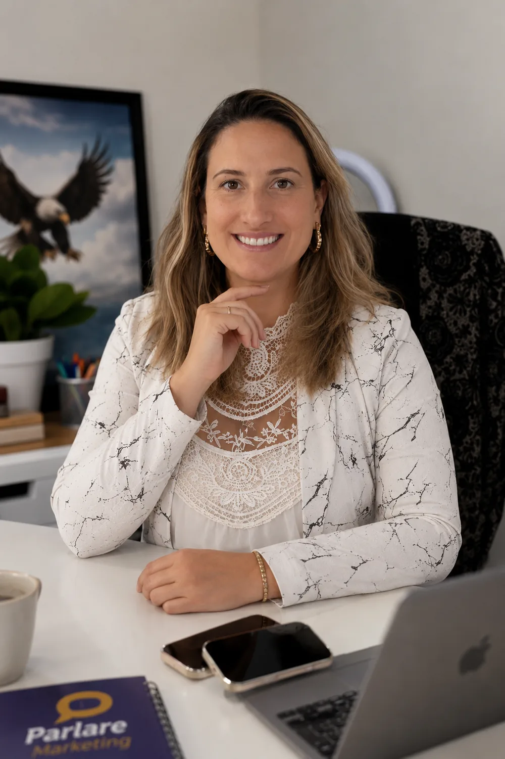 Mariana Miranda sorrindo, sentada à mesa de trabalho