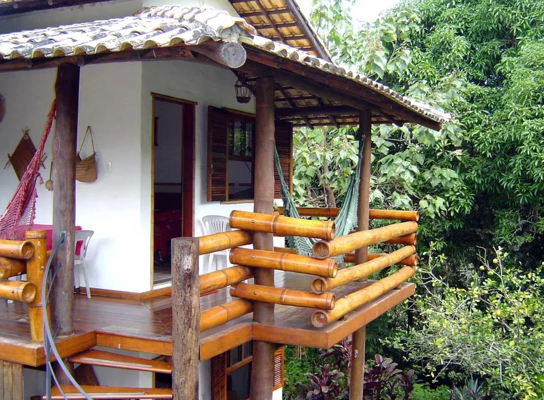 Varanda de madeira com rede, cercada de árvores